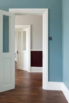 an empty room with blue walls and white trim on the door, hardwood flooring