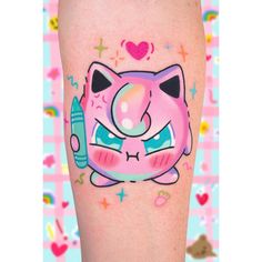 a cat tattoo on the leg of a person with pink and blue designs around it