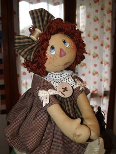 a stuffed doll with red hair wearing a dress