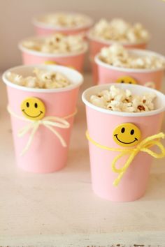 pink cups with smiley faces on them and popcorn in the middle one cup is filled with rice