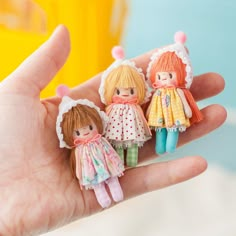 three little dolls are sitting on the palm of someone's hand in front of them