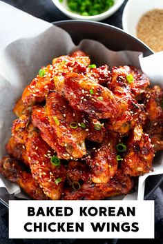 a bowl filled with chicken wings covered in sauce and green onions