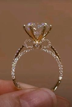 a person is holding up a diamond ring in their left hand, with the center stone on