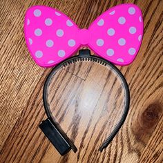 a pink minnie mouse ears headband with white polka dots on it and a black clip