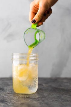 a person pouring lemonade into a mason jar