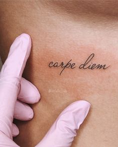 a person with gloves on their hands is holding up a tattoo that reads carpe diem