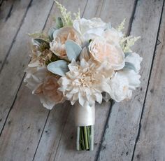 a bridal bouquet with white and pink flowers on a wooden floor in front of a window