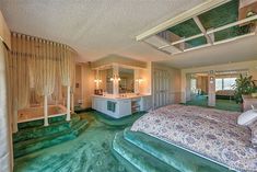 a large bedroom with green carpeting and white walls, along with an enormous bed in the center