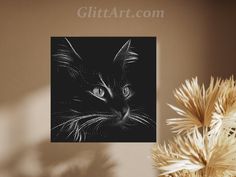 a black and white photo of a cat's face on a wall next to a potted plant