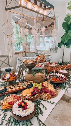 a table filled with lots of food on top of a white table covered in greenery