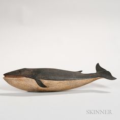 a small wooden whale sitting on top of a white surface