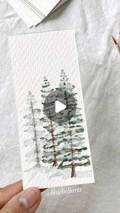 someone is holding up a card with watercolor trees on it