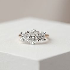 three stone diamond ring sitting on top of a white box