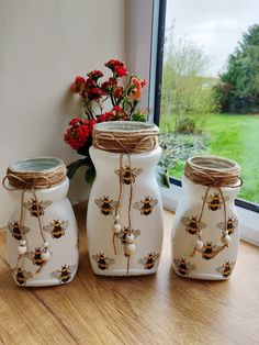 three ceramic jars with bees on them sitting next to a window