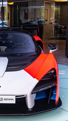 an orange and white sports car is parked in front of a glass storefront window