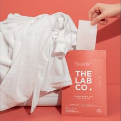 a person holding a white towel next to a pink bag with the label the lab co on it