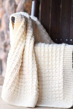 a white crocheted blanket sitting on top of a wooden chair