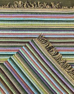 multicolored striped rugs with tassels and fringes laid out on top of each other