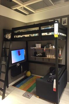 a loft bed with a desk underneath it and a television on the bottom shelf in front of it