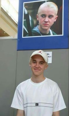 a young man standing in front of a poster with a photo of him on it