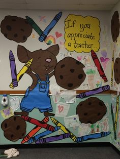 a classroom wall decorated with an image of a bear holding pencils and crayons