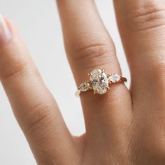 a woman's hand with a diamond ring on top of her finger and an engagement band