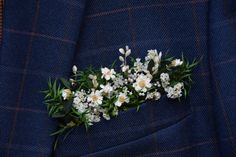 a boutonniere with white flowers and greenery on a blue suit jacket