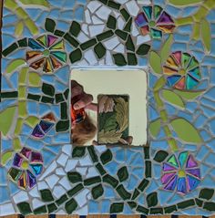 there is a colorful mosaic with a cat in the center and a hand reaching for something