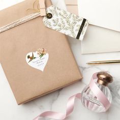 a gift wrapped in brown paper next to a pink ribbon