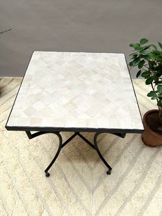 a table with a tiled top next to a potted plant