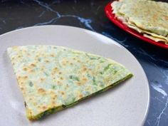 two pieces of flat bread on a white plate next to another piece of tortilla