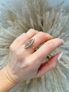 a woman's hand with a diamond ring on top of her finger and feathers in the background