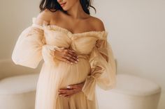 a pregnant woman in a dress poses for a photo with her hands on her belly