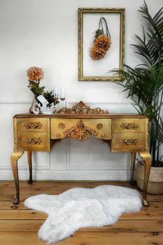 an antique desk with gold paint and white fur rug