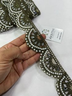 a hand holding a tie that has been made with beads and pearls on it,