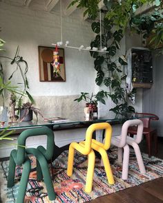 three colorful chairs sitting on top of a rug in front of a table with potted plants