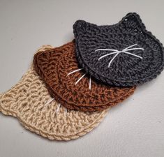 three crocheted coasters with cats on them