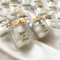 small glass containers filled with candles on top of a white cloth covered tablecloths