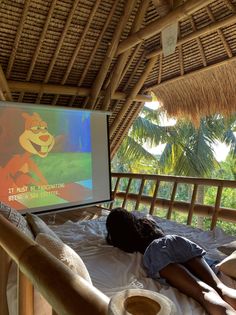 a person laying on a bed in front of a projector screen with an animated character