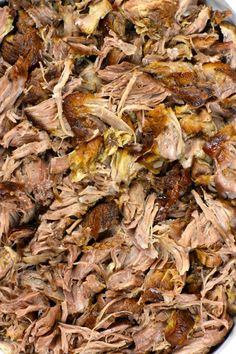 shredded pork in a white bowl on a blue and pink tablecloth with spoons