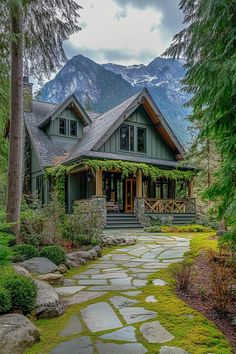 a house in the woods with green grass and rocks on the walkway leading to it