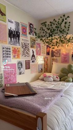 a bed with lots of posters on the wall above it and a book laying on top