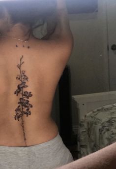 the back of a woman's body with flowers on her left side, behind which is a mirror