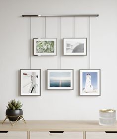 a white wall with pictures hanging on it's sides and a plant in the middle