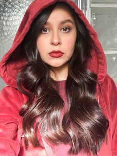 a woman with long dark hair wearing a red hoodie and looking at the camera