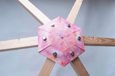 a pink object with metal studs on it sitting on top of a wooden cross