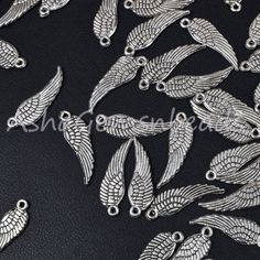 some silver metal birds on a black leather surface with white stitching and beads in the middle