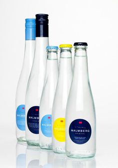 four bottles of water are lined up on a white surface, one is blue and the other has yellow