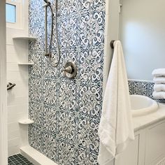 a bathroom with blue and white tiles on the shower wall, tub and towel rack