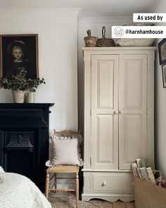 a bedroom with a white armoire next to a black fire place and pictures on the wall